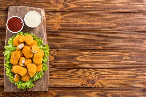 Nuggets de pollo en plato sobre fondo rústico —  Fotos de Stock