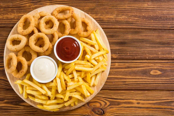 Patatine fritte e anelli di cipolla con salse — Foto Stock