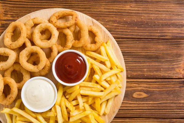 Patatine fritte e anelli di cipolla con salse — Foto Stock