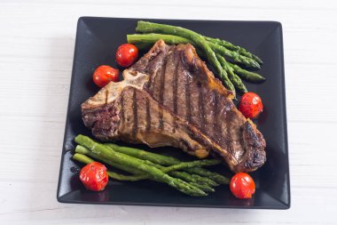 Kuşkonmaz ve kiraz domatesli ızgara biftek. T kemik eti.