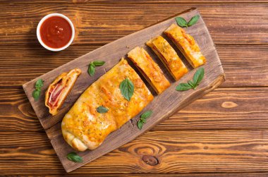 Italian food Pizza roll stromboli with cheese , salami , olives and tomatoes  clipart