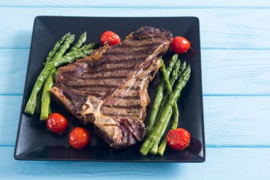 Kuşkonmaz ve kiraz domatesli ızgara biftek. T kemik eti.