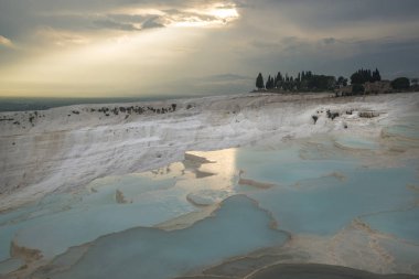 Güneş bulutların arasından kırdı ve Pamukkale mavi göller kompozisyon ortasına yaktı