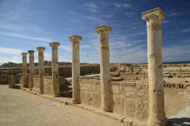 Mavi gökyüzü bulutlar arka plan ile karşı iyonik büyük harfler ile antik sütunlar. Küçük mavi deniz ortasında görünür. Salamis şehir harabeleri, Kuzey Kıbrıs.