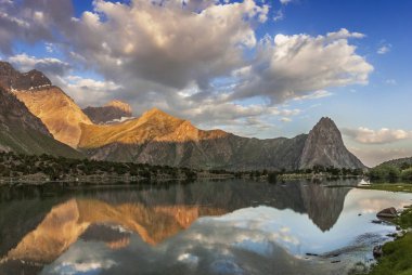 Güneşli dağ Kulikalon gölde yansıtır. Büyük beyaz bulut ile mavi gökyüzü kompozisyon tatlar.