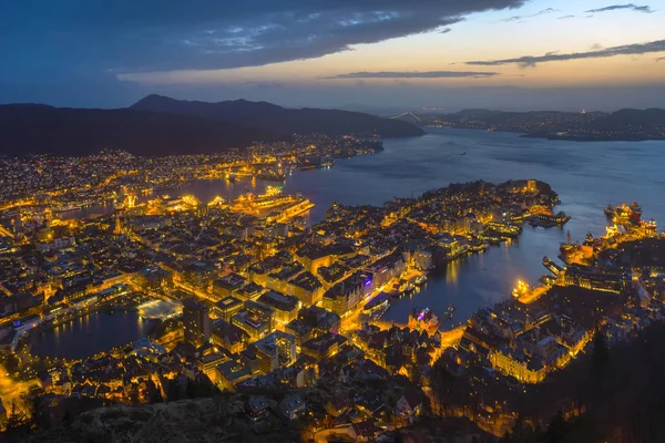 Bergen town night view (west coast of Norway). Town is illuminated. Sunset sky and blue sea in the background.