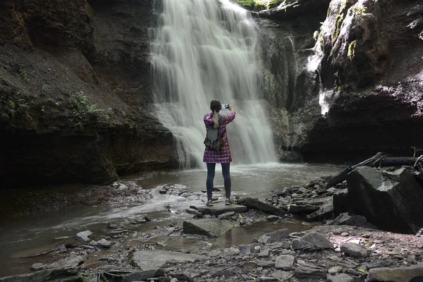 Girl photographs waterfall with phone