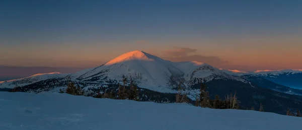 Wintermorgen in den Bergen. beleuchteter Berggipfel in der Mitte — Stockfoto
