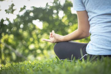 Kadın yoga yapıyor ve meditasyon yapıyor, dışarıda egzersiz yapıyor, doğa rahatlığını yakından görüyor, sağlıklı yaşam tarzı kavramını kavrıyor..