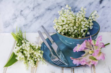 Bahar sofra Vintage mavi çatal bıçak takımı, Lily vadi çiçek ve üzerinde bir mermer Background.Floral Masa desenli pembe lale