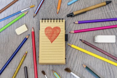 Ahşap arka planda dizüstü bilgisayar lı renkli kalemler