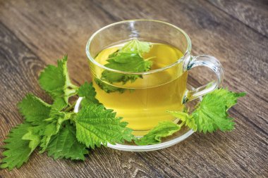 Cam bardak çay mermer zemin üzerine taze ısırgan otu ile