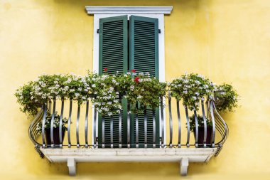 İtalya yeşil çiçekli balkonlar ile sarı ev