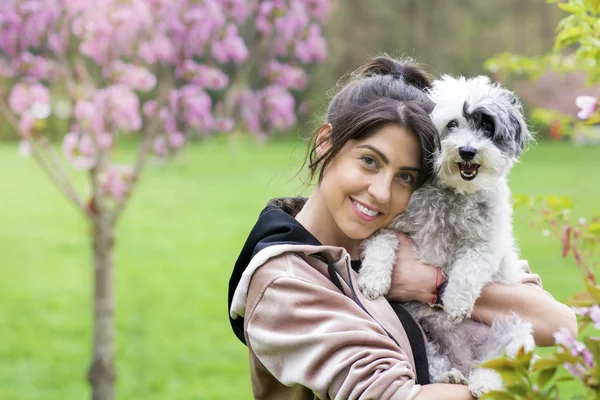 Güzel gülümseyen kadın onu sevimli Havanese köpek sarılma. Evde beslenen hayvan ve sahip açık bahar