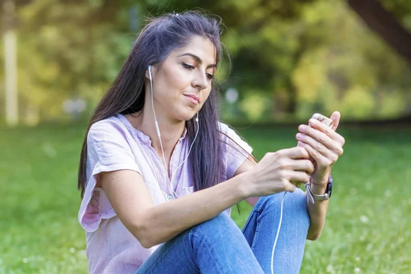 Mujer Joven Con Auriculares Escuchando Música Teléfono Inteligente Parque —  Fotos de Stock