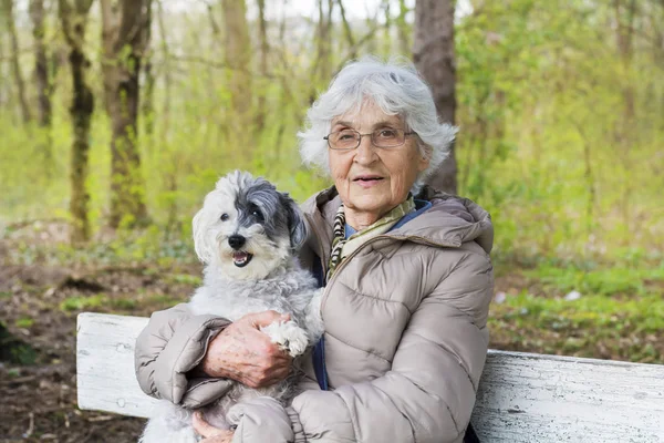 快乐微笑的高级妇女抱着她的狗在春天的公园 — 图库照片
