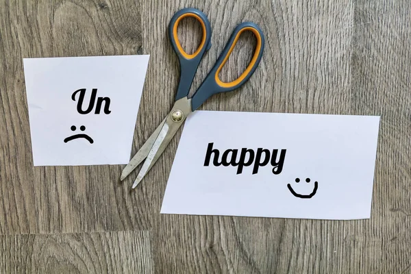 Unhappy Concept with Scissors Cutting  off the Word Un of Unhappy