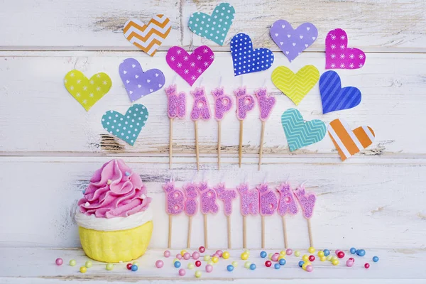 Pink Happy Birthday Candles,Cupcake and Colorful Hearts on a White Wooden Background