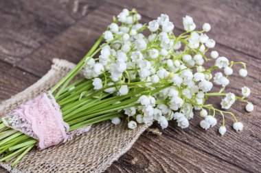 Ahşap arka plan üzerinde pembe kurdele ile Lily vadi buket. Bahar çiçekleri arka plan