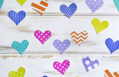 Beyaz ahşap arka plan üzerinde renkli kağıt kalp tebrik kartı