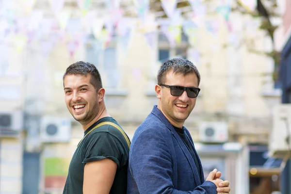İki gülen erkek arkadaş poz ve kentsel sokakta eğlenmek 