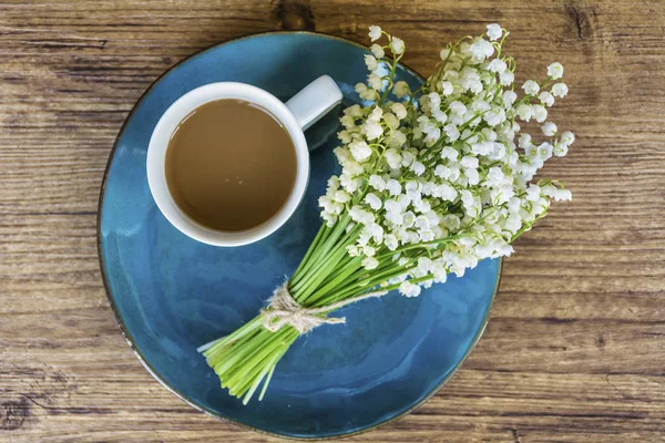 Spring Table Setting with Vintage Blue Cutlery and Lily of the Valley Flowers on a Wooden Background.Floral Table Decor with Coffee Cup.Top view