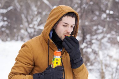 Genç adam kış dağda sıcak çay içme 