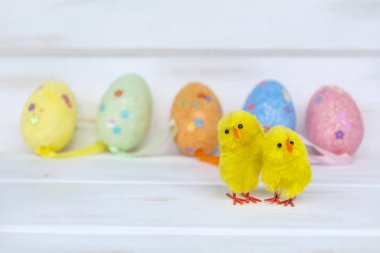 Paskalya yumurtaları ve beyaz ahşap zemin üzerine sarı tavuk