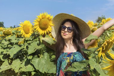 Ayçiçeği alanındaki hasır şapkalı güzel genç kadın