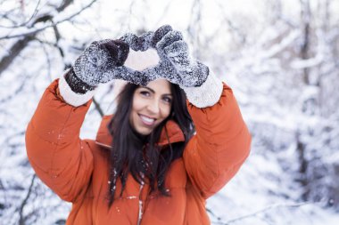 Kalp Eller ile bir kış Snowy orman yapma güzel gülümseyen genç kadın. Kış Holidays.Selective odak