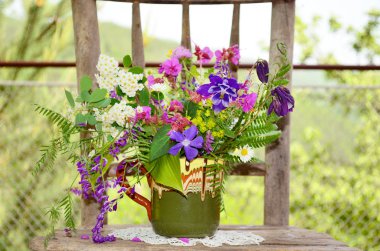 ahşap sandalye üzerinde renkli çiçekli vazo