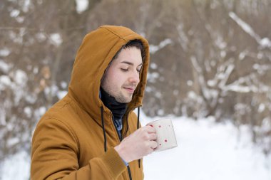 Genç adam kış dağda sıcak çay içme 