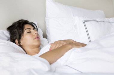 Beyaz rahat yatakta uyuyan genç kadın
