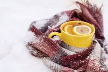 bir fincan çay limon dilimi kar üzerinde örme atkı sarılı