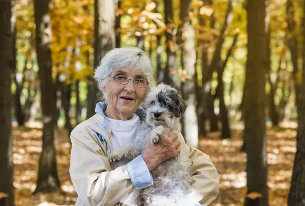 Beautiful Happy Senior Woman Hugging her Cute Havanese Dog Outdoor in the Summer Mountain.Woman and Dog Traveling Together