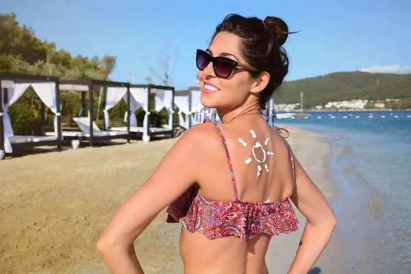 beautiful woman with suntan lotion sunscreen solar cream on the beach
