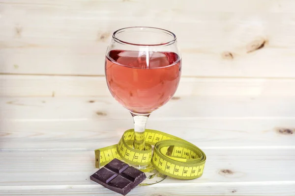 glass of wine with measuring tape and chocolate .Calories in alcohol are extra-fattening