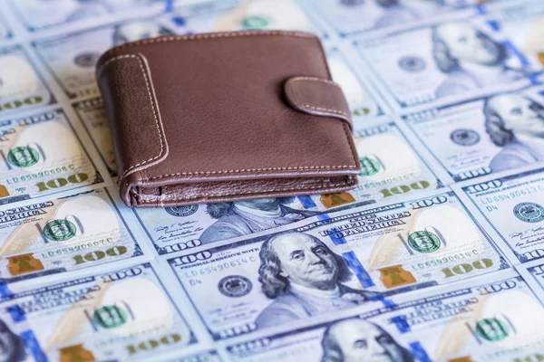 Brown leather wallet on stacks of the United States dollar