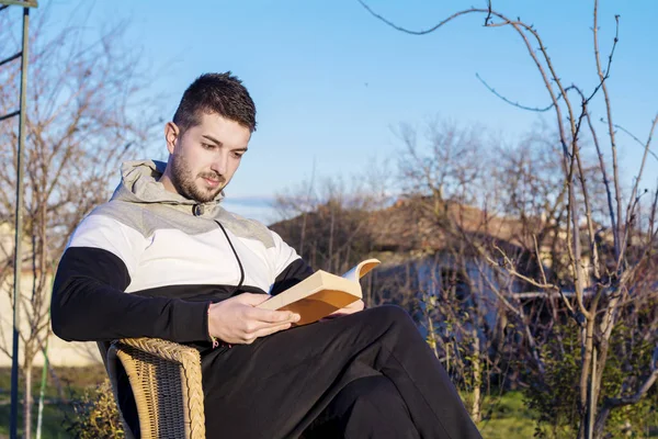 Sandalyede Oturan Kitap Okuma Genç Adam — Stok fotoğraf