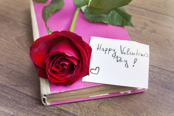 Cute rose on pink book with lettering. Valentine\'s Day concept.