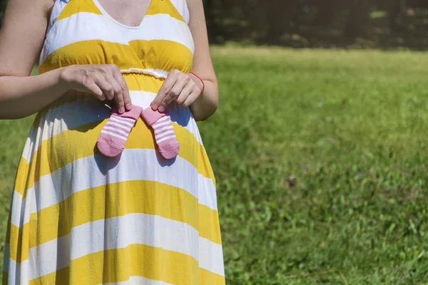 赤ちゃんの靴下を持って若い妊婦 — ストック写真