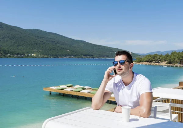 Hombre Gafas Sol Hablando Teléfono Inteligente Cafetería Cerca Del Mar — Foto de Stock