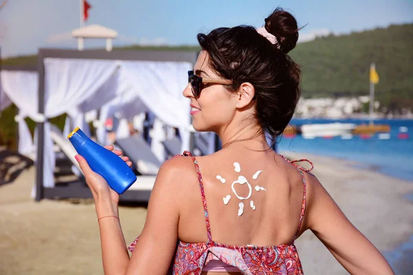 beautiful woman with suntan lotion sunscreen solar cream on the beach