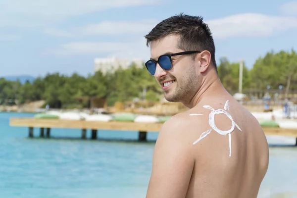 Sun symbol made by skin cream on back of young man
