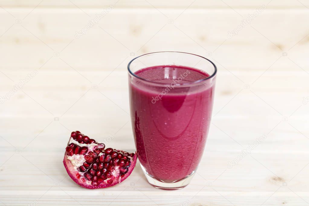A glass of ripe pomegranate juice on wooden background. Healthy living concept.
