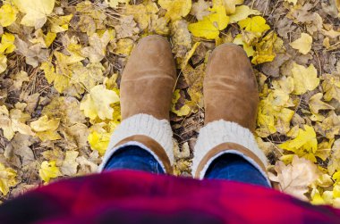Parkta sarı düşmüş sonbahar yaprakları üzerinde Kadın çizmeler