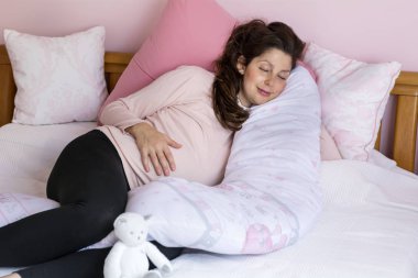 yastık destekleyen karın ile rahat uyuyan güzel hamile kadın