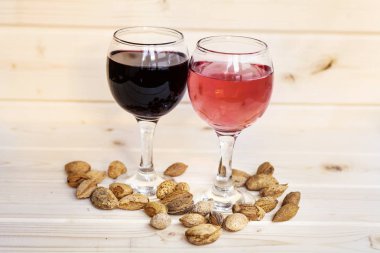 Kırmızı şarap bardak , gül ve fındık ahşap bir arka plan üzerinde. Romantik tarih kavramı