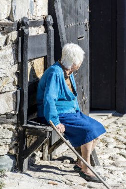 Gri saçlı yaşlı kadın kentsel sokakta bankta oturan