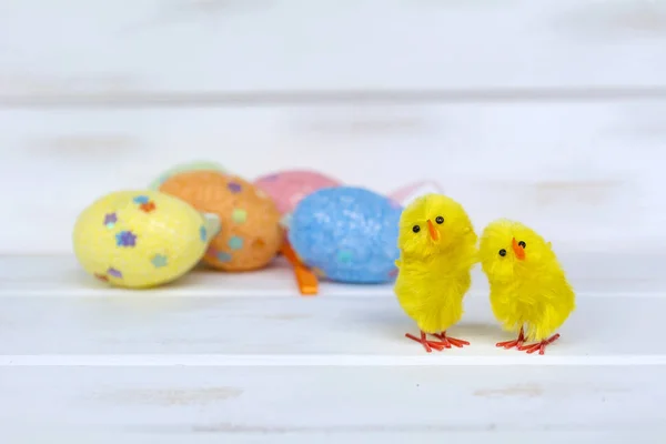 easter eggs and yellow chickens  on a white wooden background